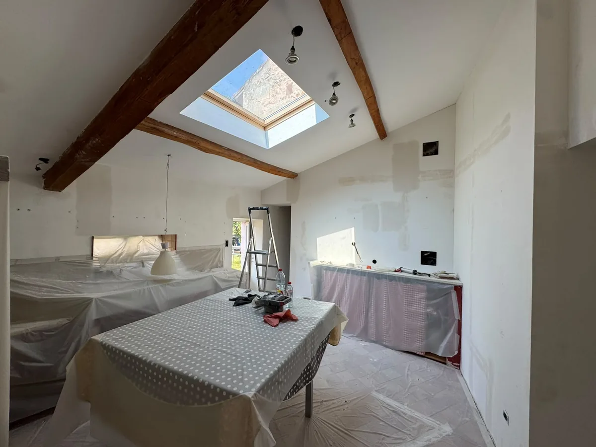 Cuisine intégralement protégée avant peinture : meubles, plan de travail et sol bâchés, reprises à l'enduit sur les murs