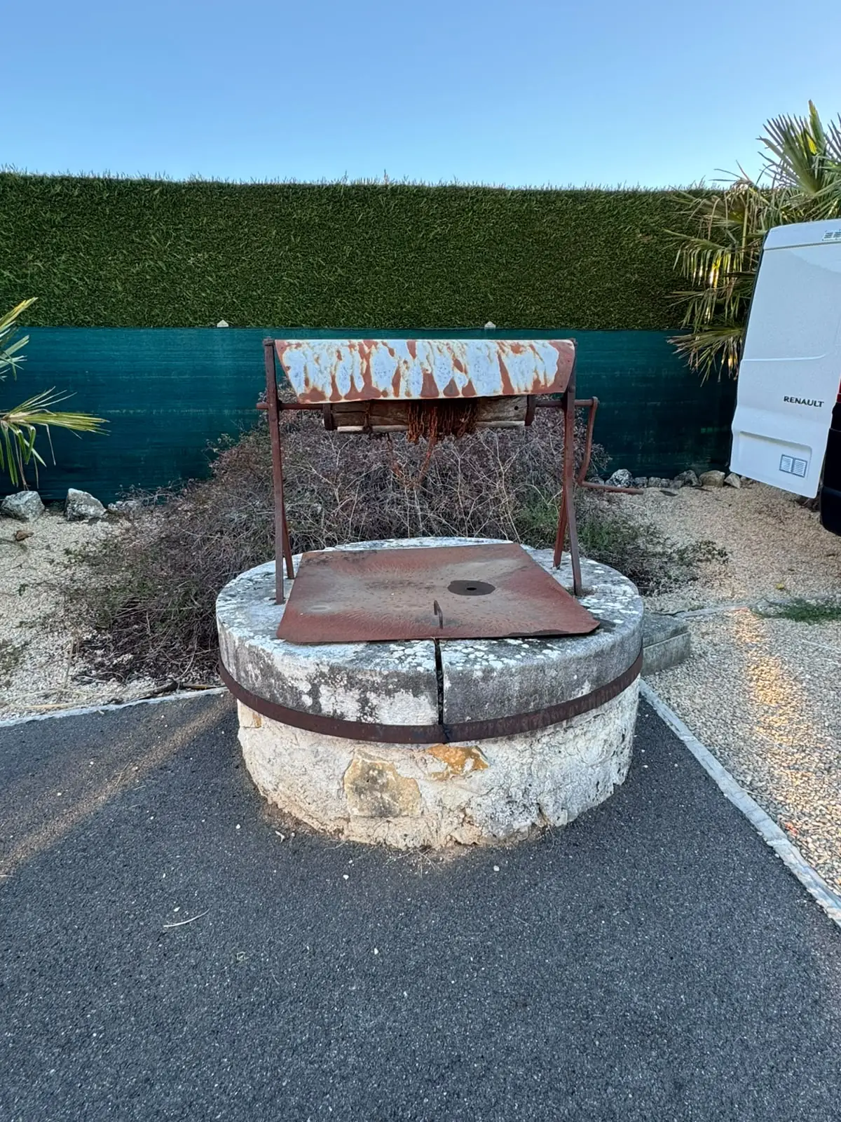 Puits en pierre avant rénovation, toit et plaque de couverture en tôle entièrement rouillés, cerclage métallique corrodé et pierre couverte de lichen